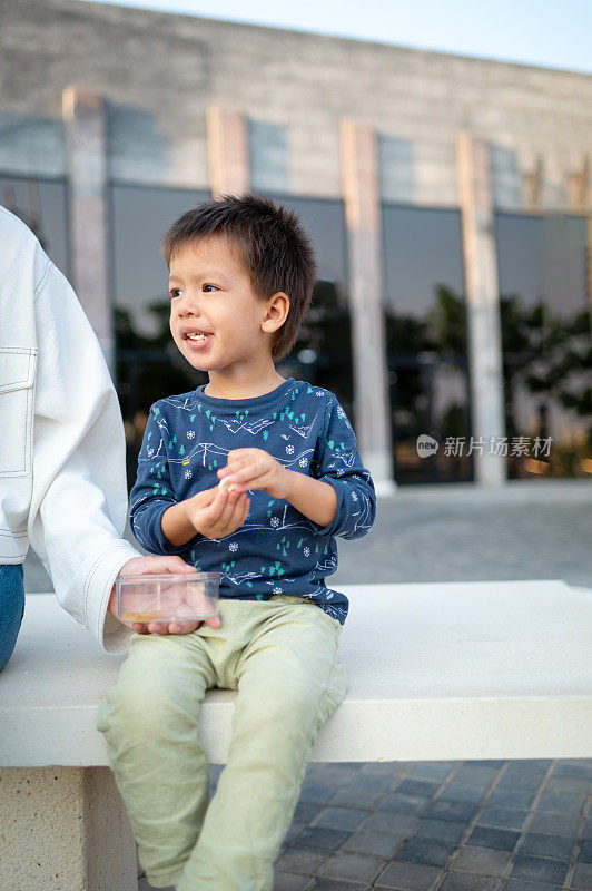 木板路上的甜蜜时刻:多种族小孩和妈妈一起享受零食