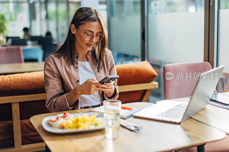 一位女商人在餐馆点了一份酱汁烤鸡。在她开始吃饭之前，她会用手机