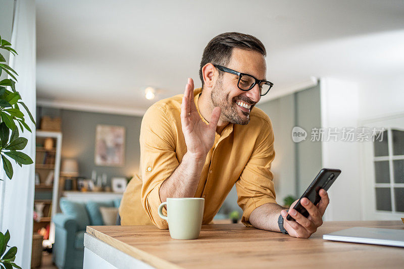 英俊的中年白人男子在家里的客厅用手机自拍或打视频电话