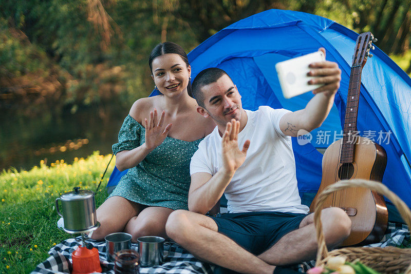 一名年轻男子和一名女子在露营时使用数码平板电脑。