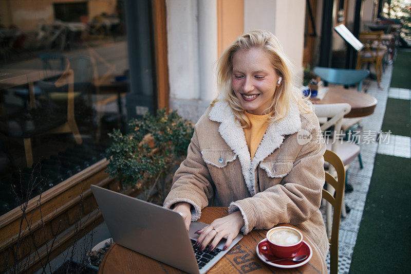 年轻的白化病妇女在咖啡馆使用笔记本电脑