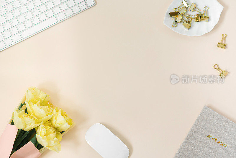 平面放置博主或自由职业者的工作空间，配有记事本、键盘和一束黄色牡丹郁金香
