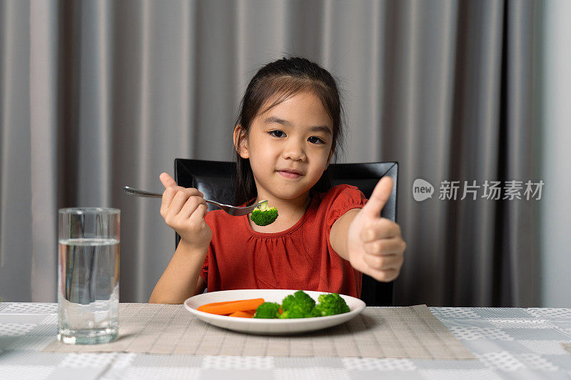 可爱的小女孩展示拇指，展示吃健康蔬菜。