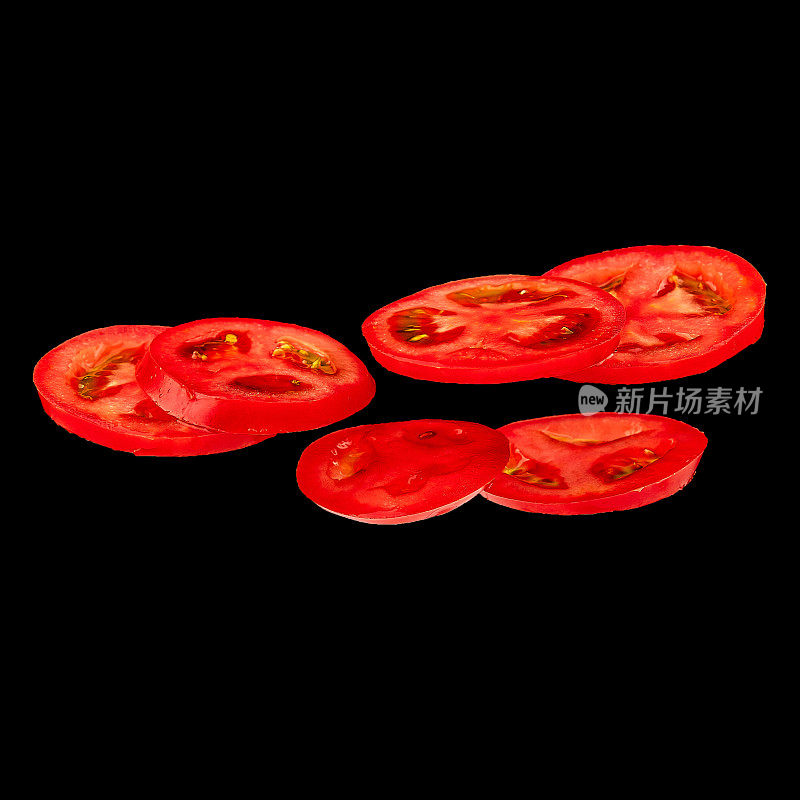 飞行的番茄。切片红番茄孤立在黑色背景。轻浮的蔬菜漂浮在空中。