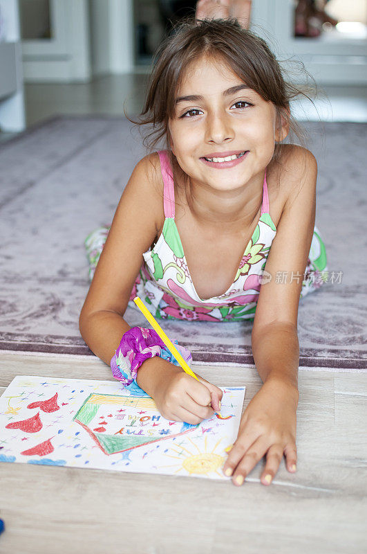 可爱的小女孩在家画画，在纸上写着“呆在家里”的话