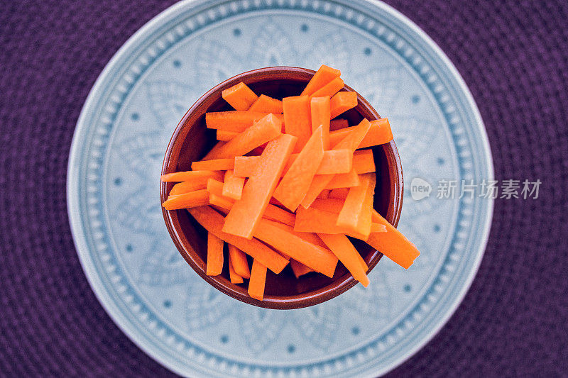 切好的胡萝卜放在碗里，配上深紫色的背景