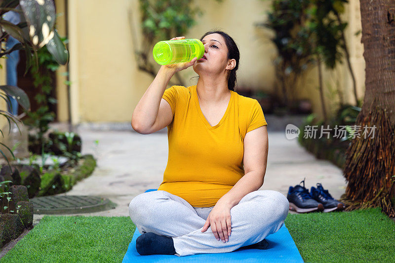 女人在做晨练和瑜伽的时候喝水。