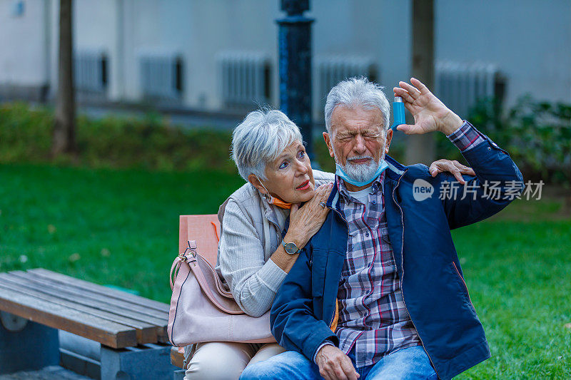 老年妇女正在为患有哮喘的丈夫提供帮助，以克服呼吸问题。