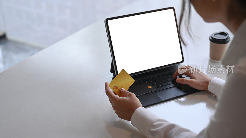 近距离观察年轻女性使用平板电脑和持有信用卡进行网上购物或在线支付。