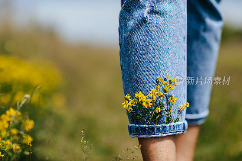 光着脚的年轻女子在田园诗般的野花地里