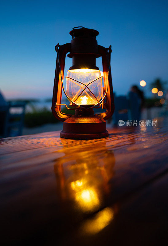户外餐厅的桌子上放着一盏古董灯笼，背面是大海