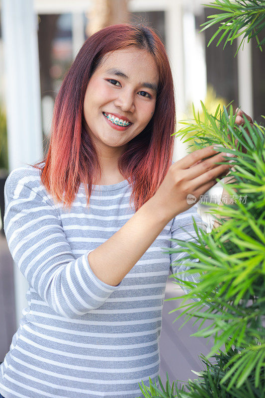 年轻的泰国女子站在一棵树上开心地微笑