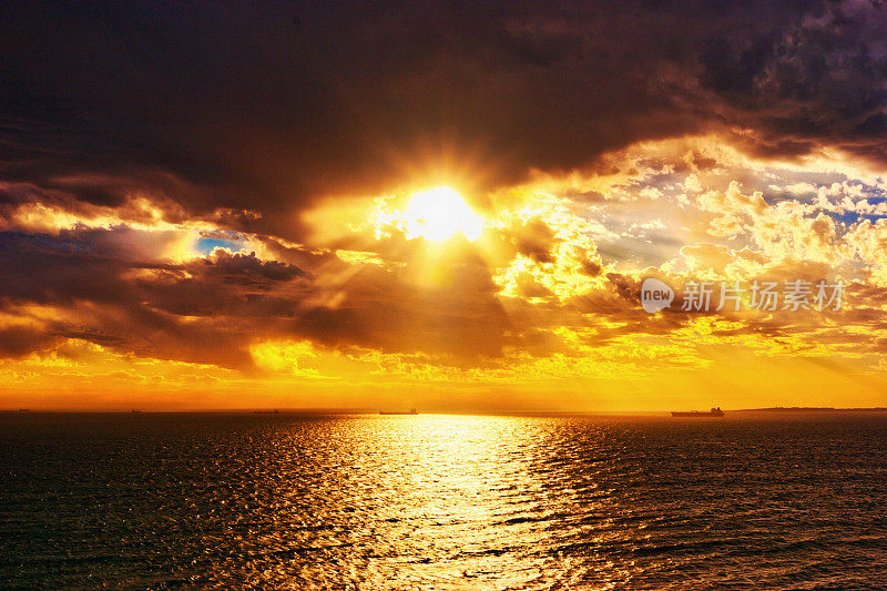 壮观的日出或日落在美丽的波光粼粼的海面上，与小船只靠近地平线