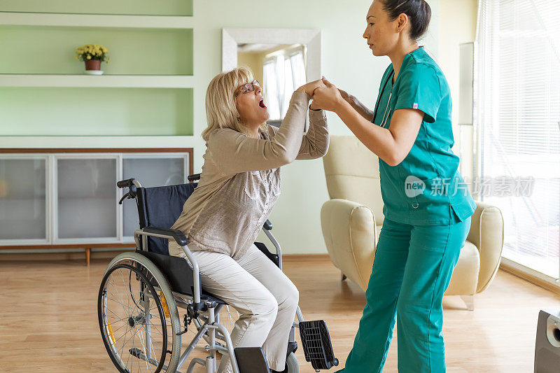 一位年长的残疾妇女正在接受一位女性看护者的帮助，她正试图把她扶起来。