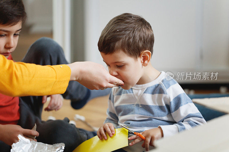 蹒跚学步的孩子剪着纸吃着妈妈的手