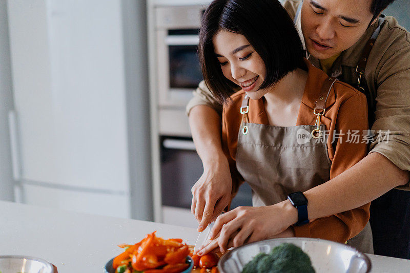 年轻的亚洲夫妇切菜准备做饭