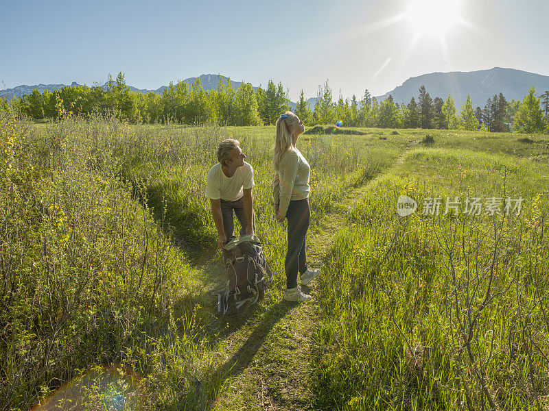 徒步旅行的夫妇沿着小路穿过绿色的高山草地