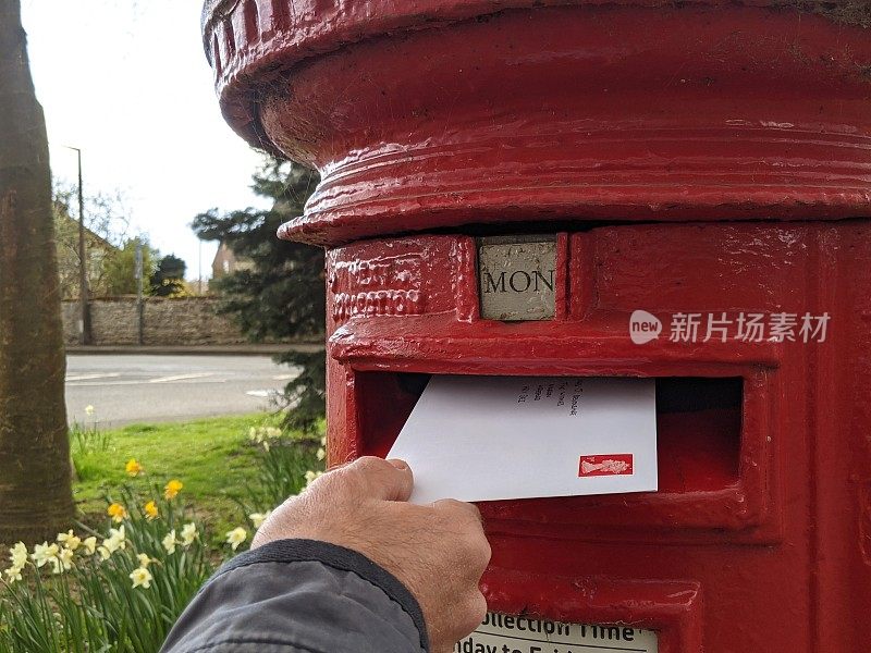 在乡郊的邮筒内手动投寄贴有邮票的信件