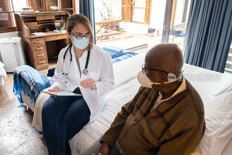 医生使用数字平板电脑在家里与病人交谈-戴口罩