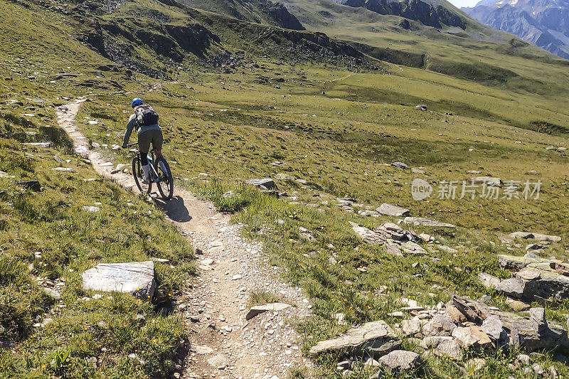 女人沿着阳光明媚的自行车道骑山地车