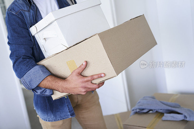 中年男子拿着纸盒搬进新房
