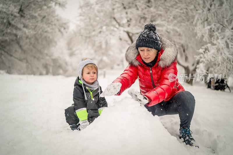 家庭妈妈和孩子一起在雪地里玩冬季活动