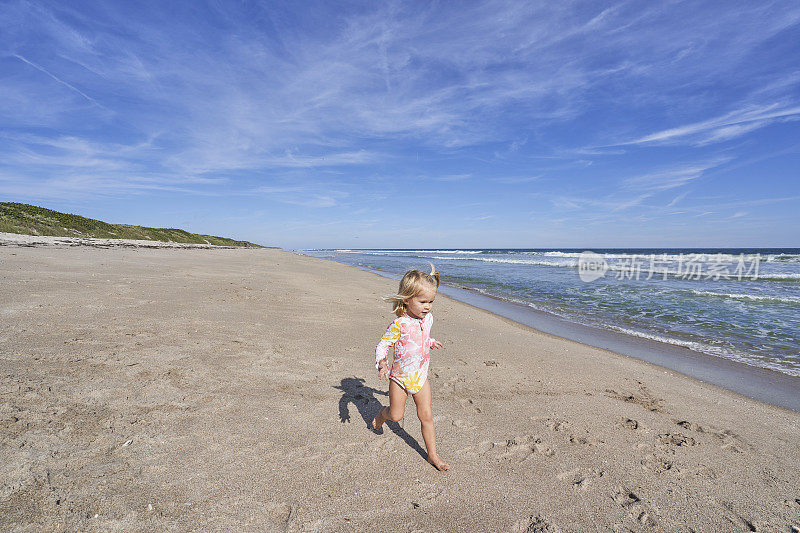 在佛罗里达州梅里特岛国家野生动物保护区附近的大西洋沿岸卡纳维拉尔国家海岸美丽的Playlinda海滩上玩耍的蹒跚学步的女孩