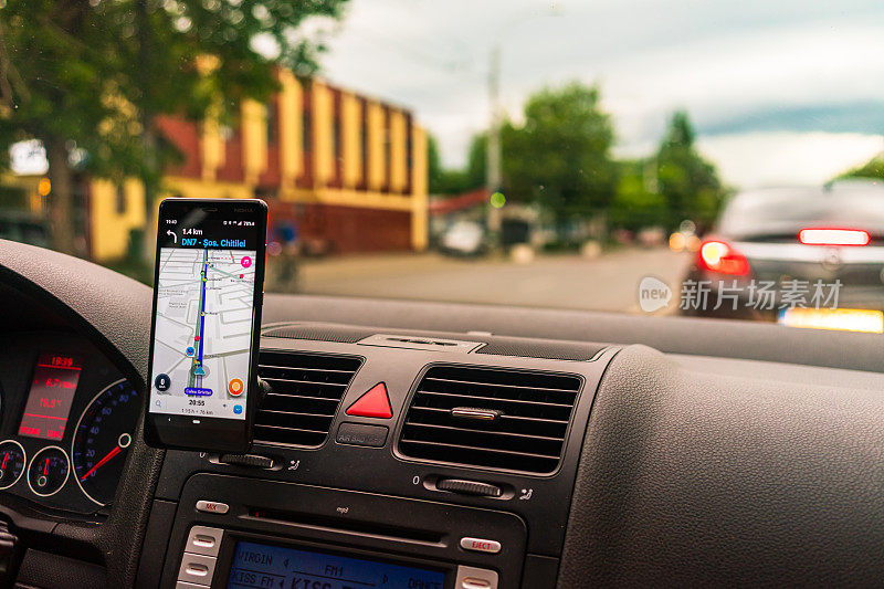 驾驶和使用waze地图应用程序在智能手机上的汽车仪表盘，司机使用地图应用程序显示通过城市交通的正确路线。布加勒斯特,罗马尼亚,2020。