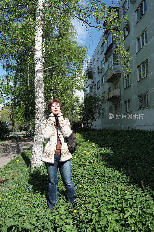 一个女人站在风飕飕的街上，把自己裹得严严实实