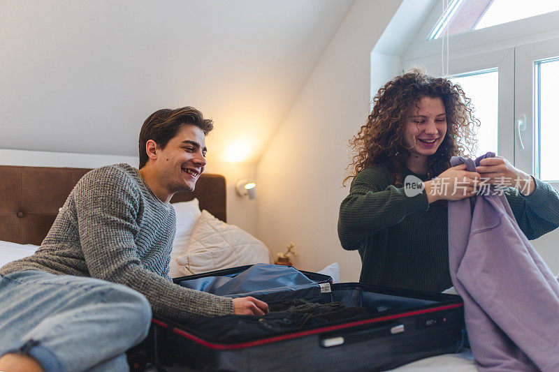 一对漂亮的年轻夫妇正在卧室里收拾行李