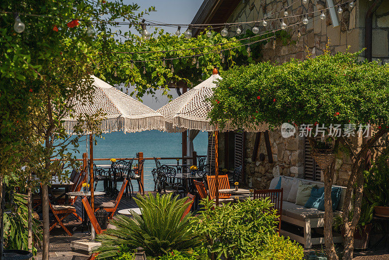 海边空荡荡的露台上有桌子和伞，夏天在欧洲的地中海度假