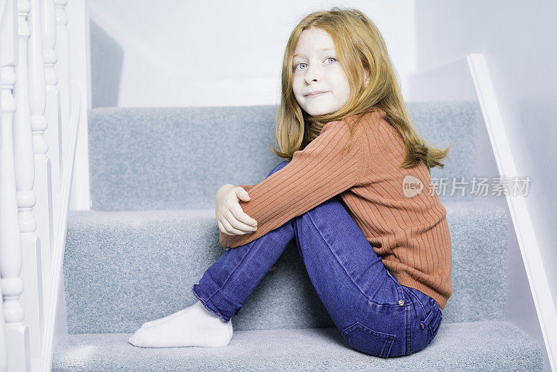 可爱的红褐色头发的女孩坐在楼梯上