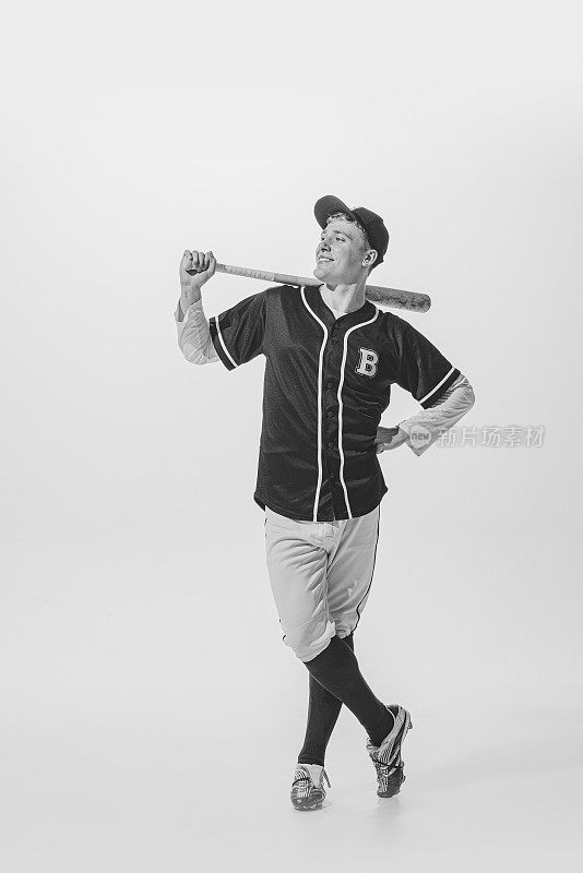 讨人喜欢的年轻人的肖像，棒球运动员，击球手在制服摆拍。黑白摄影