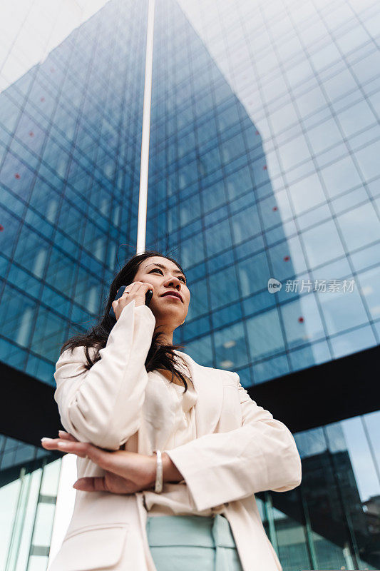 年轻优雅的中国职业商务女性在办公室外使用手机