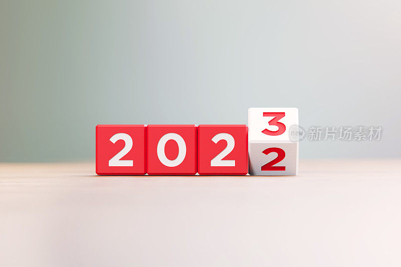 “2022”和“2023”写在离焦背景前的木头表面上的红木块