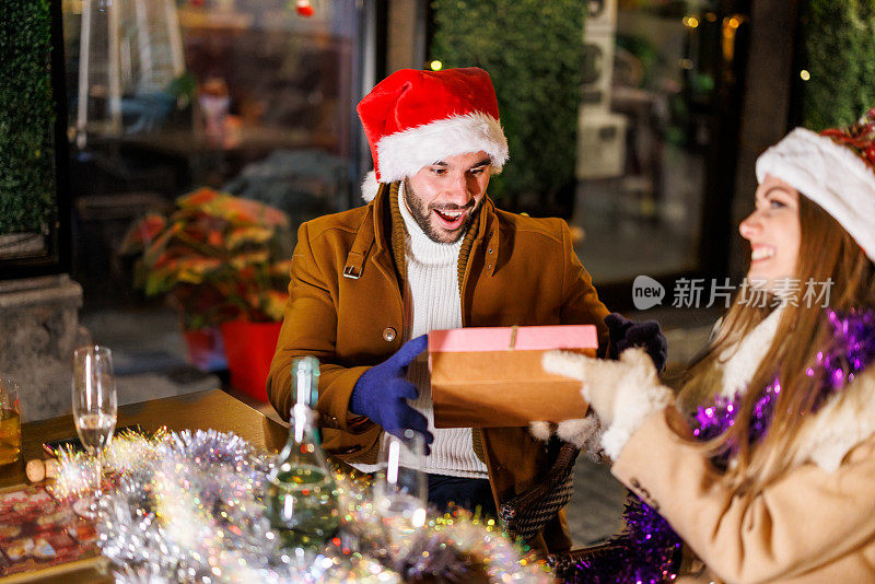 圣诞节期间，一名年轻女子和她英俊的男朋友一起在咖啡馆里享受时光。