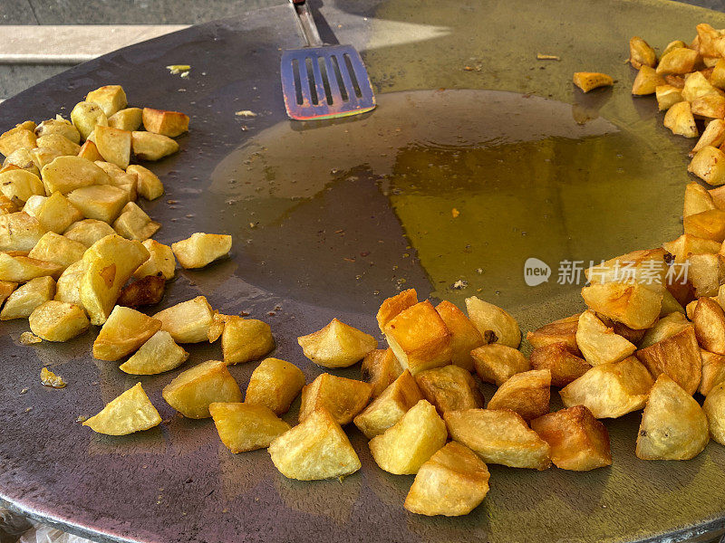 特写图像的街头食物准备在Tawa(大，扁平的金属烹饪锅)，炸土豆，食用油，金属槽铲，高架视图，重点在前景