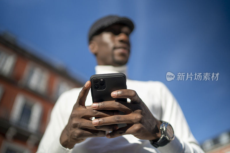 一个穿高领毛衣戴帽子的黑人拿着手机的特写镜头