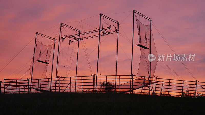 落日的天空前，自由飞翔的空中飞人栈桥的剪影