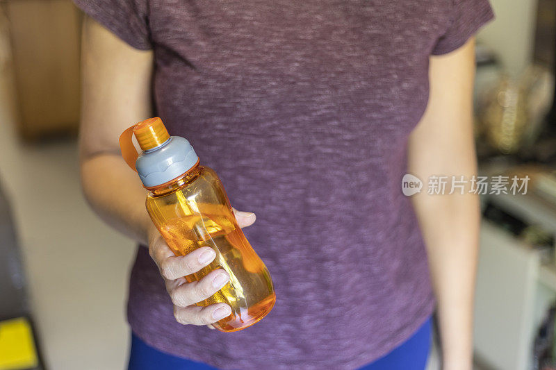 一位拉丁妇女用橙瓶里的水补水