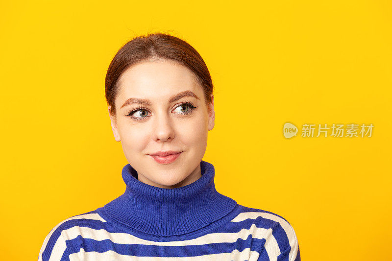 工作室肖像一个快乐的年轻白人妇女在蓝色条纹毛衣对黄色背景