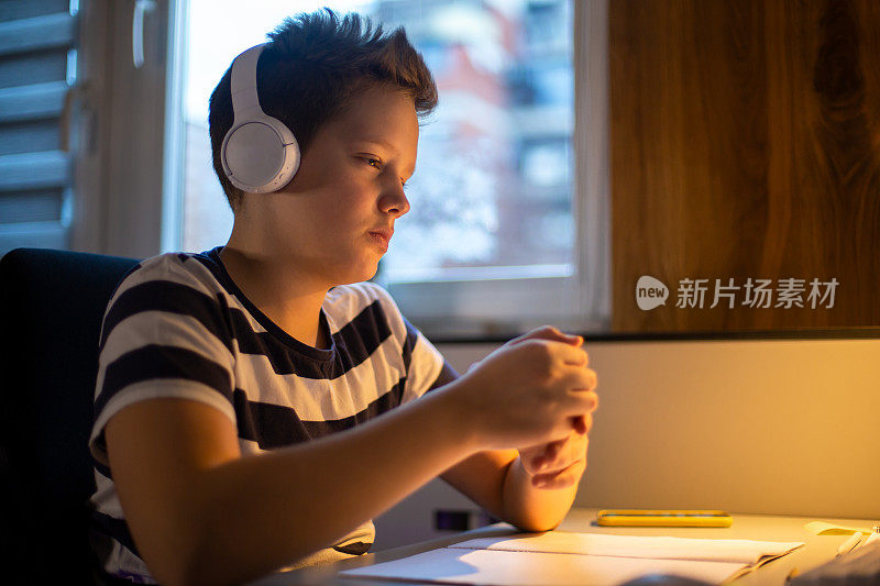 一个十几岁的男孩正在参加一个在线课程并做笔记。