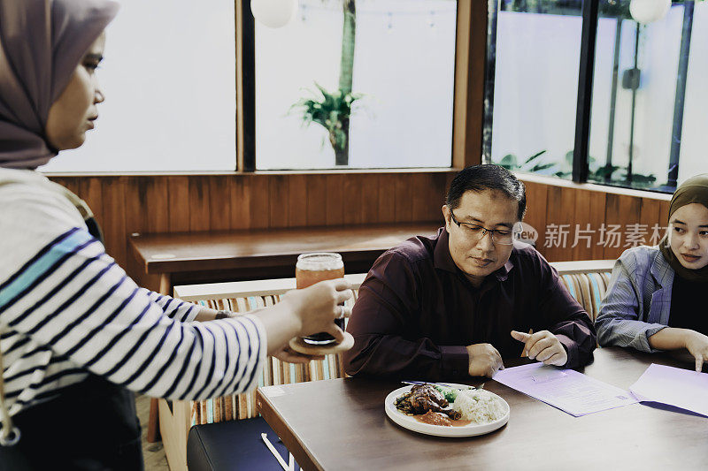 在餐馆里为一群顾客提供食物的女服务员