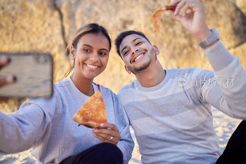 幸福的情侣，自拍和披萨，而在海滩野餐约会，与食物，电话和户外大自然的幸福。一男一女带着智能手机和午餐，同时在线更新个人资料