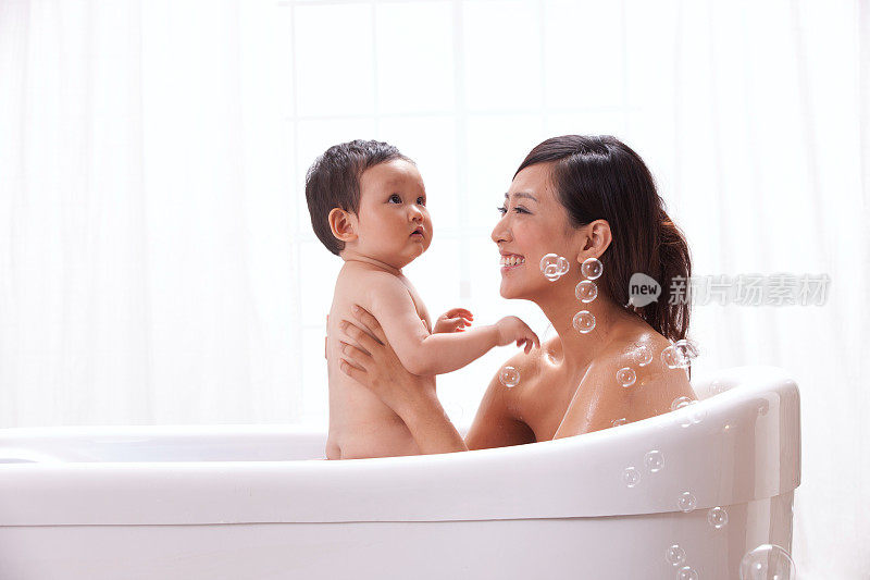母亲和婴儿坐在浴缸中洗澡