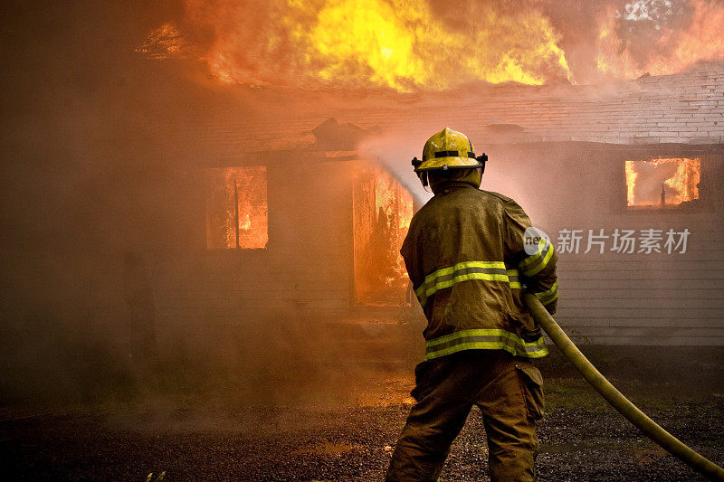 消防队员向着火的房子喷水