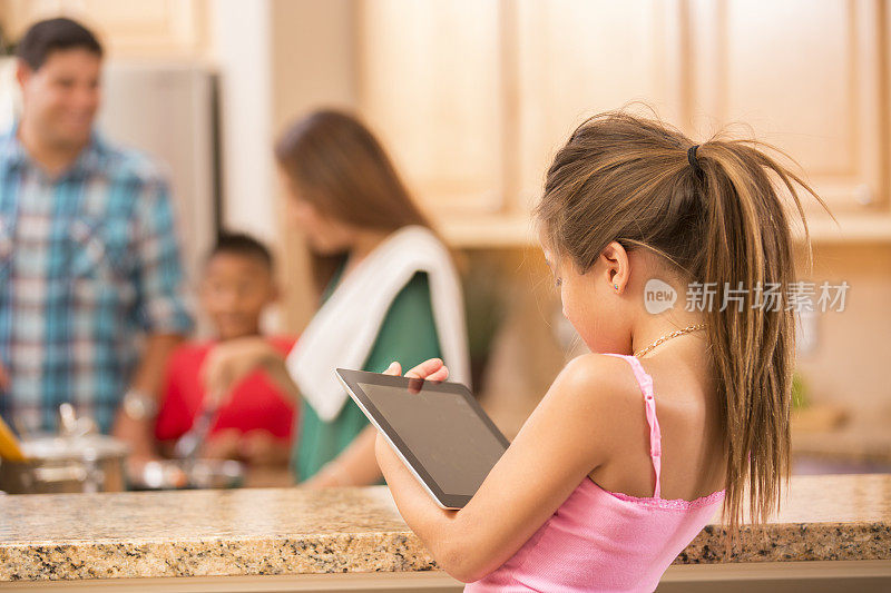有家庭烹饪背景的数字平板电脑上的小女孩。