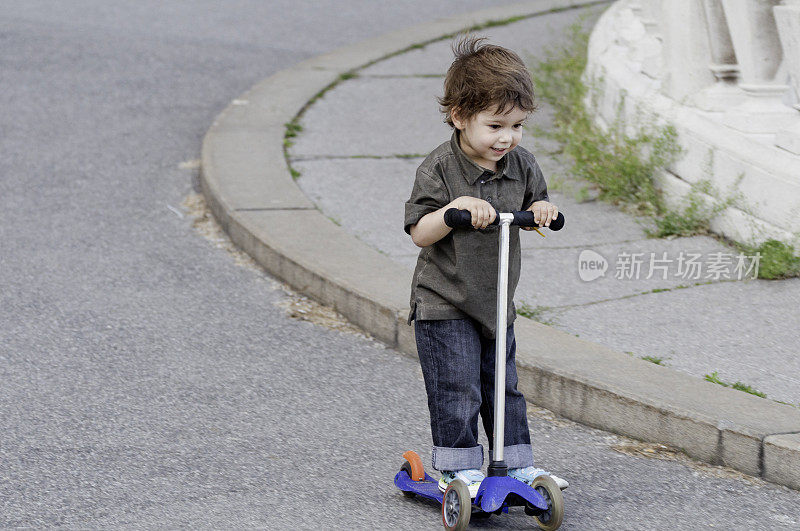 可爱的小男孩骑着滑板车
