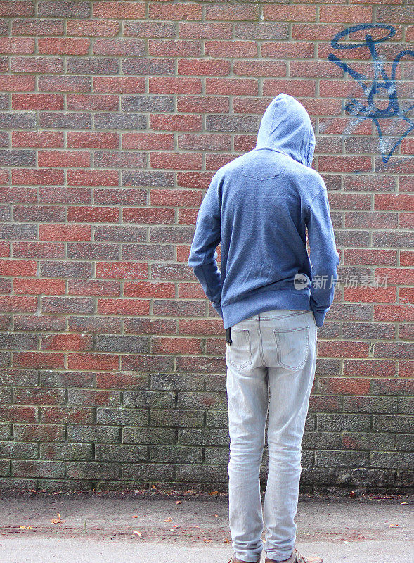 穿着连帽衫的少年形象，旁边是涂鸦砖墙
