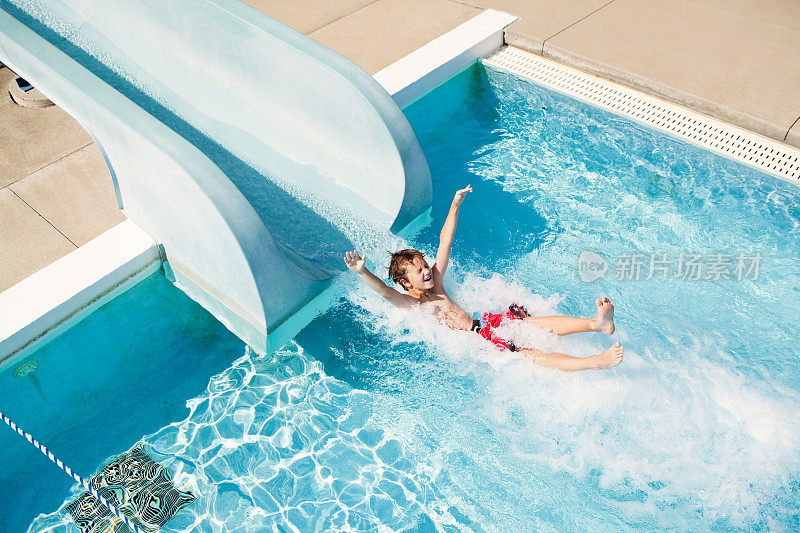 从水中滑梯出来的男孩进入游泳池